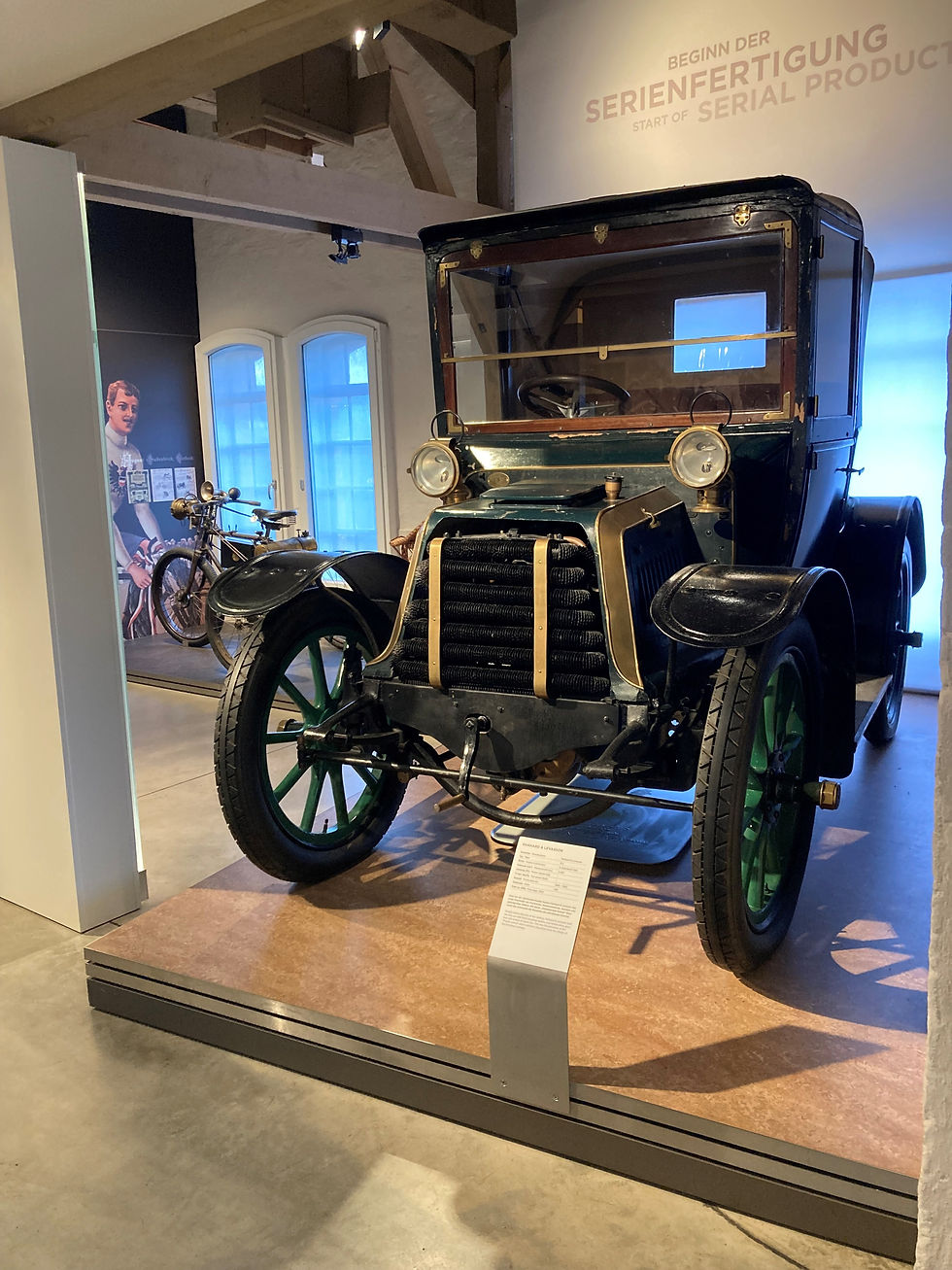 Historischer Panhard & Levassor in der Erlebnisausstellung des PS.SPEICHER, frontal auf einem Ausstellungspodest.