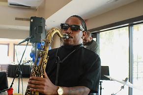 Saxophonist Jarred Armstrong playing his saxophone with a black shirt on