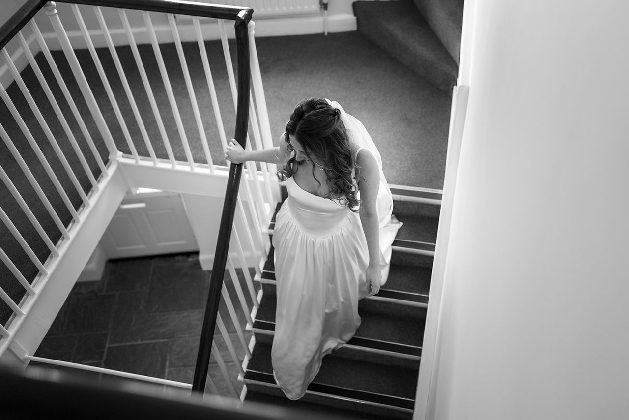 A bride gracefully descends a set of stairs at Syrencot in Wiltshire