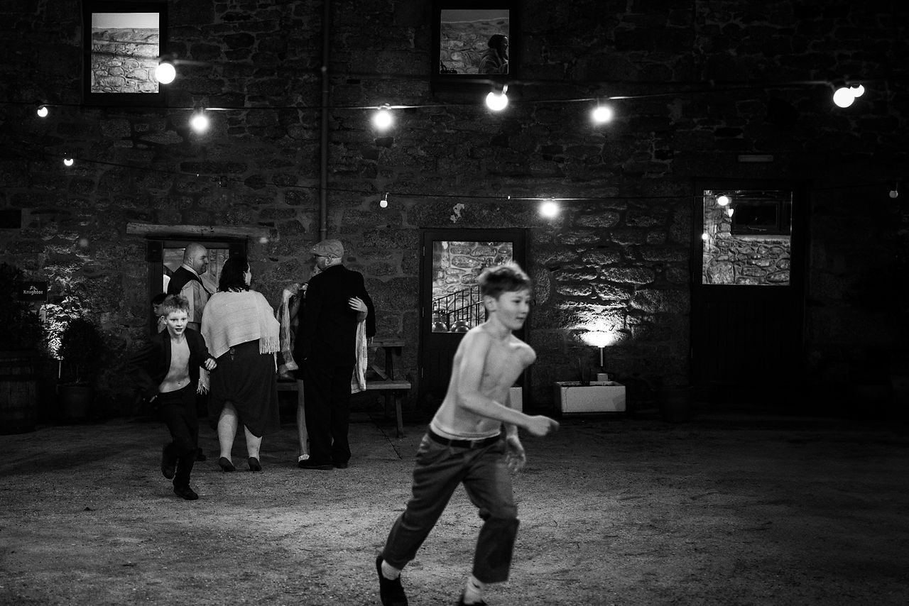 A child runs topless through a courtyard whilst being followed by another child