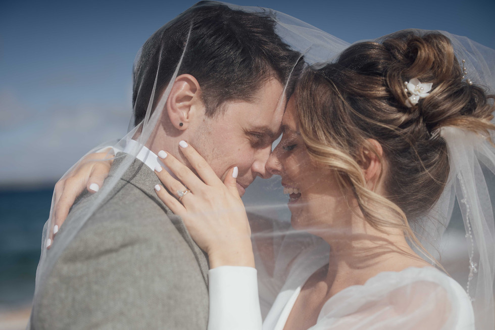 A bride and groom kiss whilst underneath the bride's veil during their wedding in St Ives, Cornwall. 
