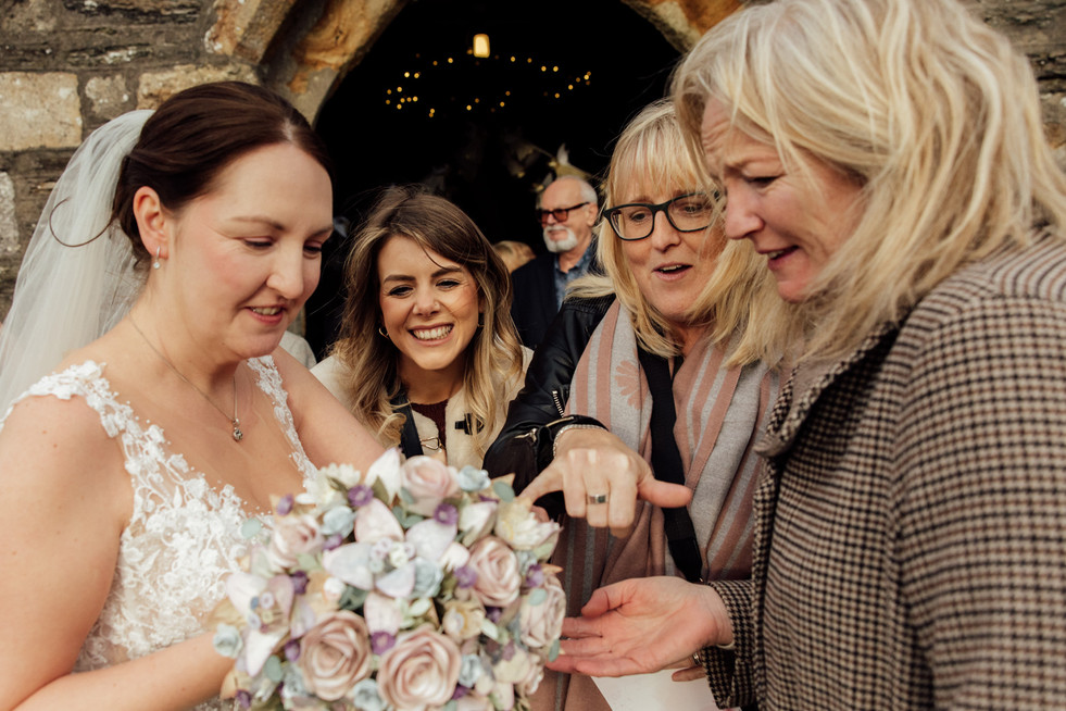 Wedding guests look at the brides wedding ring and smile