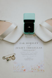 A detail shot of a bride's wedding ring, shoes and invitation capture at a Cornwall wedding by Fox and Co Photography.