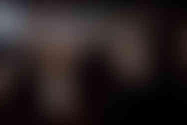 A bride raises her hands in the air whilst other guests dance together at her wedding 