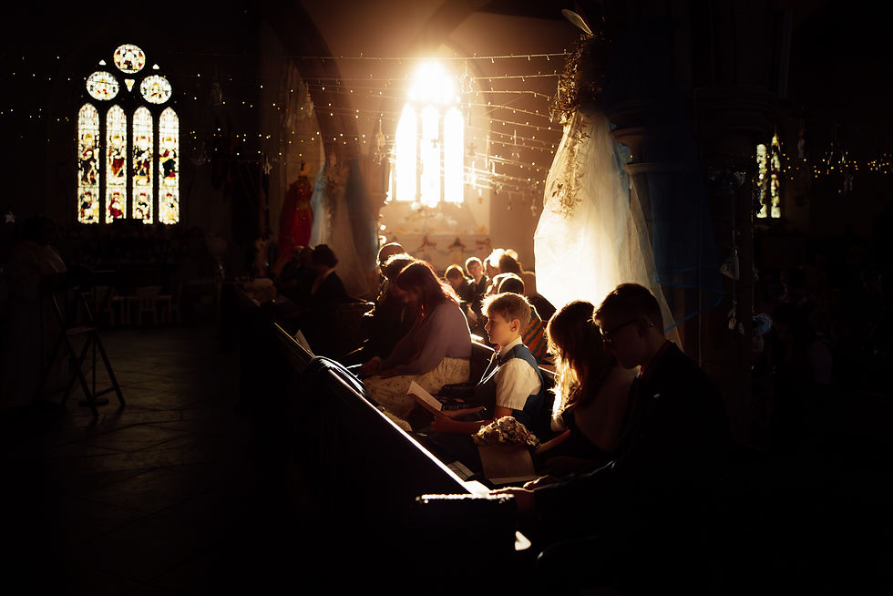 Dramatic warm sunglight pours through a church during a Devon wedding.
