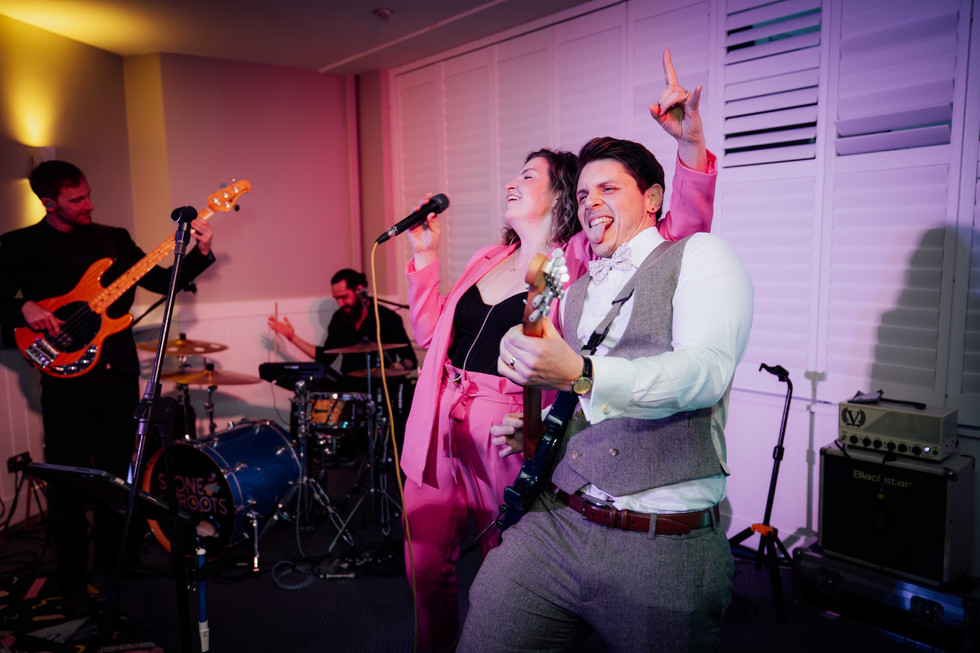 A groom performs on stage with the band at the St Ives Harbour Hotel in Cornwall, photographed by Fox and Co Photography. 