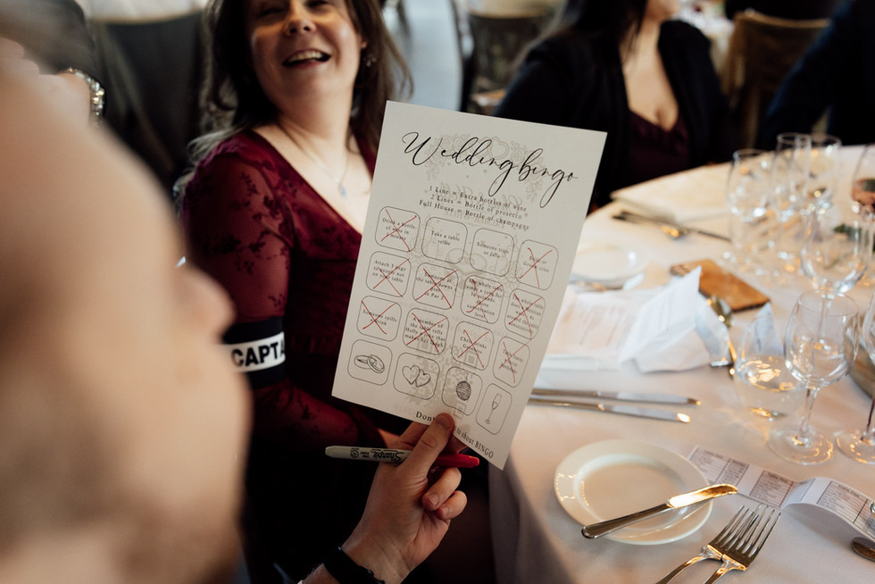 A wedding guest holds a piece of paper which reads "Wedding Bingo"