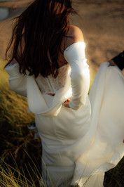 An abstract wedding photograph of a bride walking through long grass near a beach in Devon.