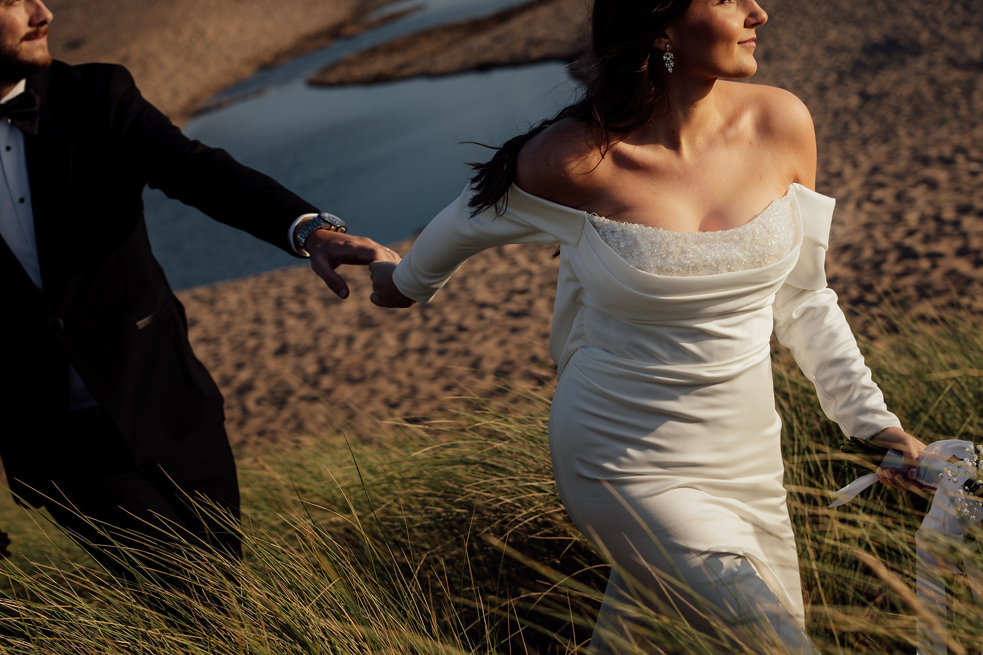 An abstract image of a bride and groom walking through long grass on a Devon coast during a wedding. 