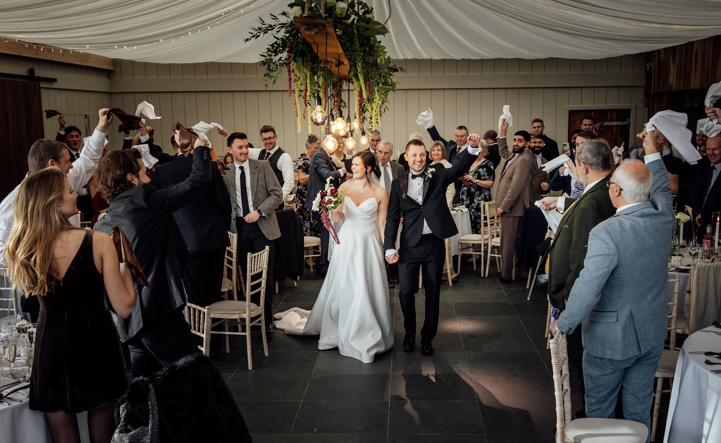 A bride and groom walk hand in hand during their wedding in Devon.