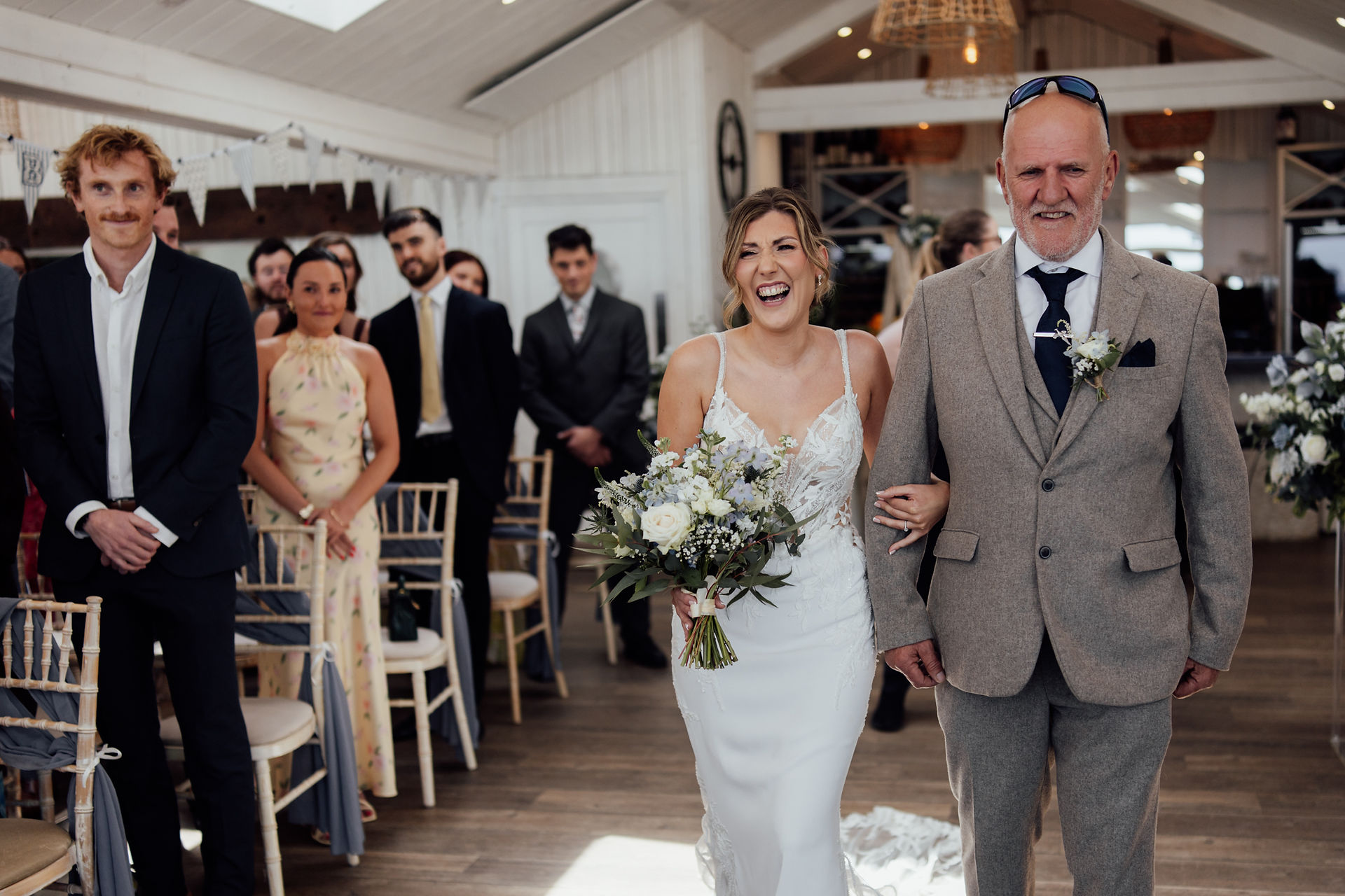 The bride laughs whilst walking down the aisle at The Carbis Bay Hotel in Cornwall during her wedding. 