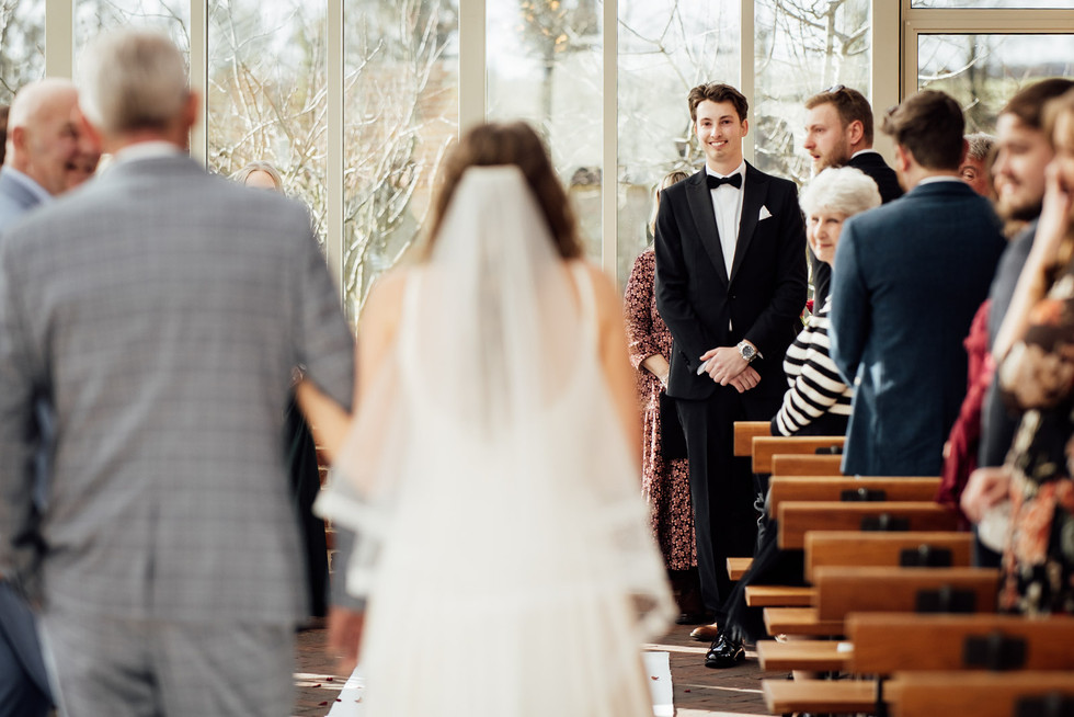 A groom reacts to seeing his bride for the first time as she walks down the aisle. 