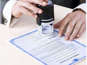 ChatGPT said: A man's hand holding a pen and notarizing a document, with an official notary stamp visible, demonstrating a professional notary service in acti