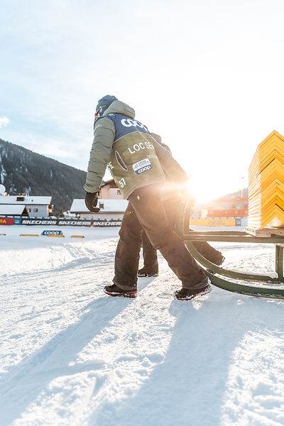 Person zieht Schlitten über verschneiten Boden im Sonnenlicht