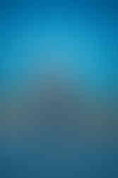 Des Moines, Iowa senior photography - teenage girl with dark hair and a cropped Iowa State Cyclone shirt poses on the rooftop during blue hour with her hand over her head and feet crossed at the ankles.