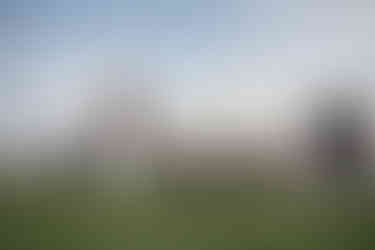 Norwalk and Des Moines, Iowa high school senior photography - football player stands on the football field holding his ball with his football helmet out in front of him on the tuf.