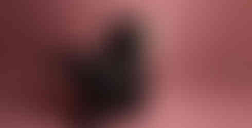 Des Moines, Iowa high school photographer - high school senior wearing a black and pink prom dress and platform shoes leans back in a black chair with one foot up against a pink backdrop.