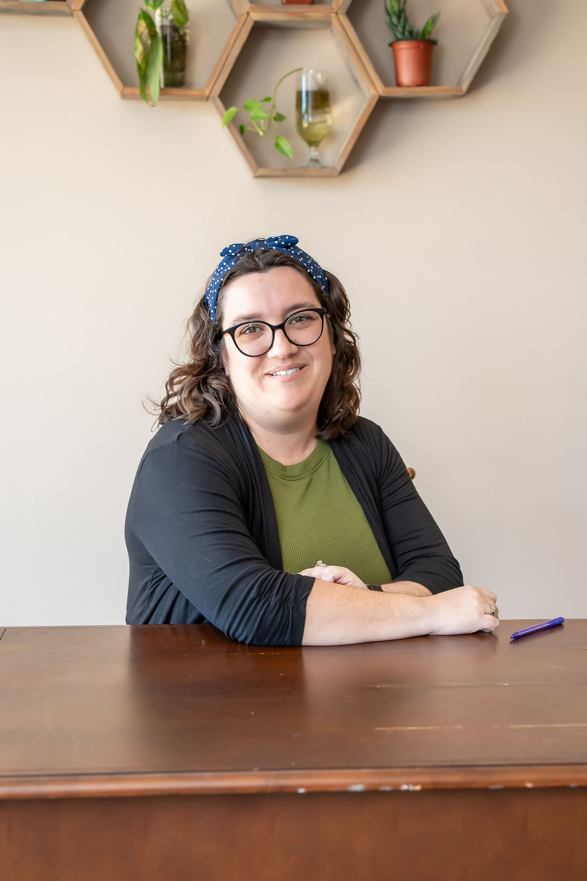 Des Moines, Iowa Branding Photographer - author Stephanie R. Caffrey poses sitting at a desk with