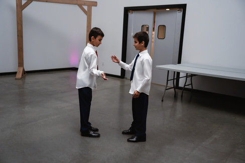 Des Moines, Iowa wedding photographer - two school-aged boys in formal wedding attire doing a handshake on the dance floor of a wedding reception.