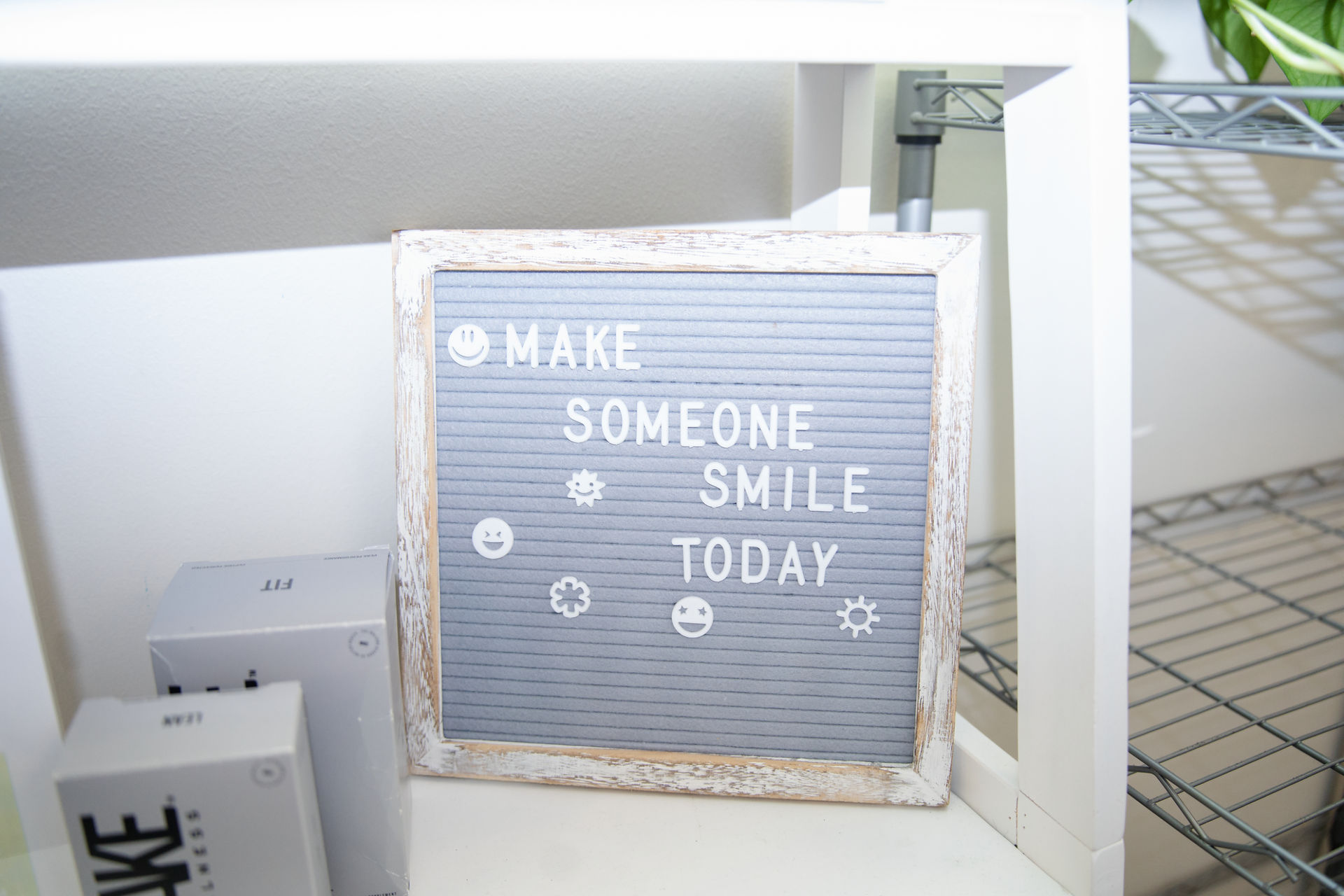 Calli Tuggle Photography - Des Moines, Iowa branding and headshot photography - a letter board sign that reads, 'Make someone smile today' on a shelf within National Health Improvement Center's Waukee clinic.