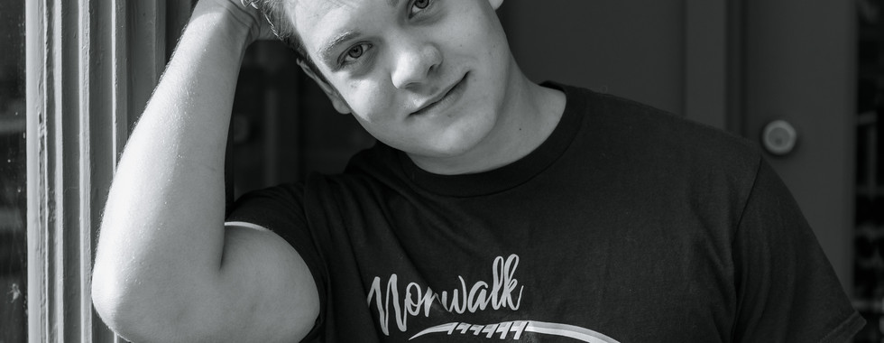 Calli Tuggle Photography - Des Moines, Iowa area senior photographer - black and white image of a male high school senior leaning against a wall with his hand running through his hair.