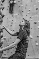 Des Moines, Iowa Photographer - Black and white image of a teenage girl with long hair bouldering at an indoor location