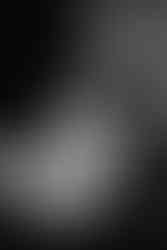 Des Moines, Iowa boudoir photography - a black and white image of a woman with dark hair in a bun wearing lingerie and an oversized sweater sitting in a leather chair looking down her shoulder.