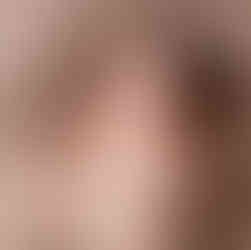 Des Moines, Iowa Newborn Photography - newborn baby boy with dark hair on a tan background with tan swaddle over him looking up and smiling