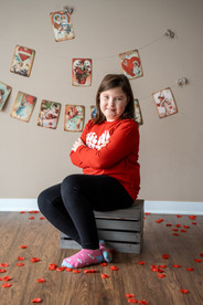 Des Moines, Iowa children and family photography - school-aged girl with brown hair and red Valentine's shirt is posed sitting.