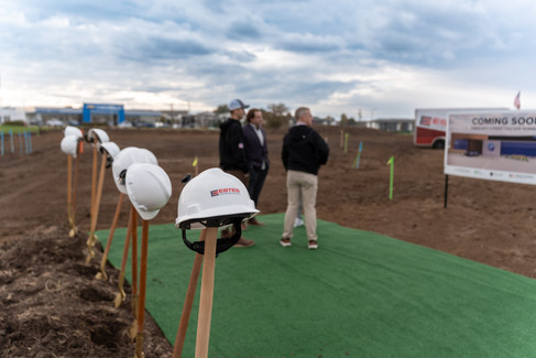 Des Moines, Iowa event photographer - a line of shovel and hard hats are in the view a group of men out of focus looking at the construction site for DMOS Orthopaedic Center's Norwalk, Iowa location.