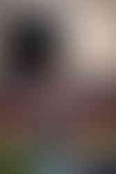 Norwalk and Des Moines, Iowa high school senior photography - football player stands on the field wearing his jersey and jeans holding a football in front of an unlit scoreboard during golden hour.