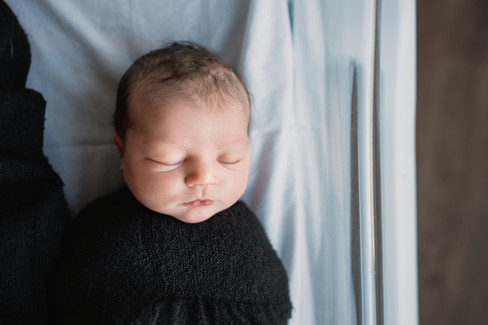 Des Moines, Iowa Fresh 48 Photographer - off-centered image of a newborn baby girl in a black swaddle in her hospital bassinet.