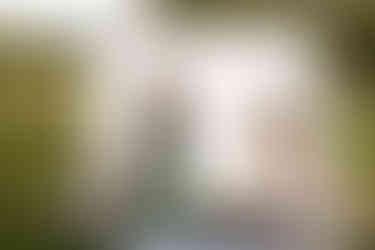 Des Moines, Iowa professional photographer - a woman with long blonde hair and a long green dress is standing in front of a white lace sheet holding a Sony camera.