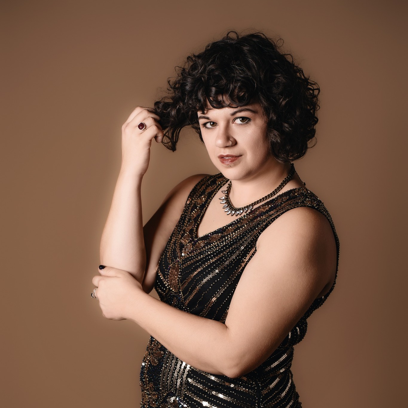 Des Moines, Iowa boudoir and glamour photographer - woman with short, curly dark hair smiles in a sparkly dress.