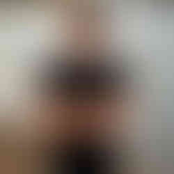 Des Moines and Norwalk, Iowa high school senior photographer - male teenager in a black t-shirt and jeans stands in front of a lake with his arms crossed over his chest.