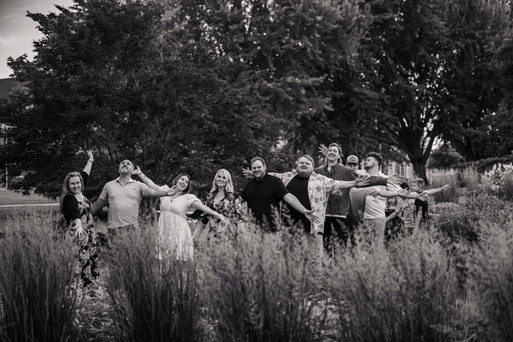 Norwalk and Des Moines, Iowa family photographer - black and white image of an extended family throwing their arms to their side for a silly pose.