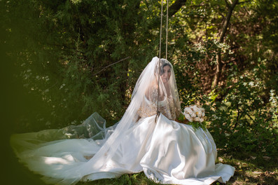 Central Iowa wedding photography - bride sits on a swing outdoors with her veil covering her face.