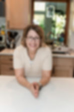 Des Moines branding photographer - adult woman in cream sweater and glasses pictured in a kitchen