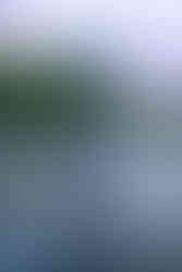 Des Moines and Norwalk, Iowa family photographer - pregnant blonde female wearing a light purple gown is posed standing in the Des Moines River looking at the camera and holding her belly.