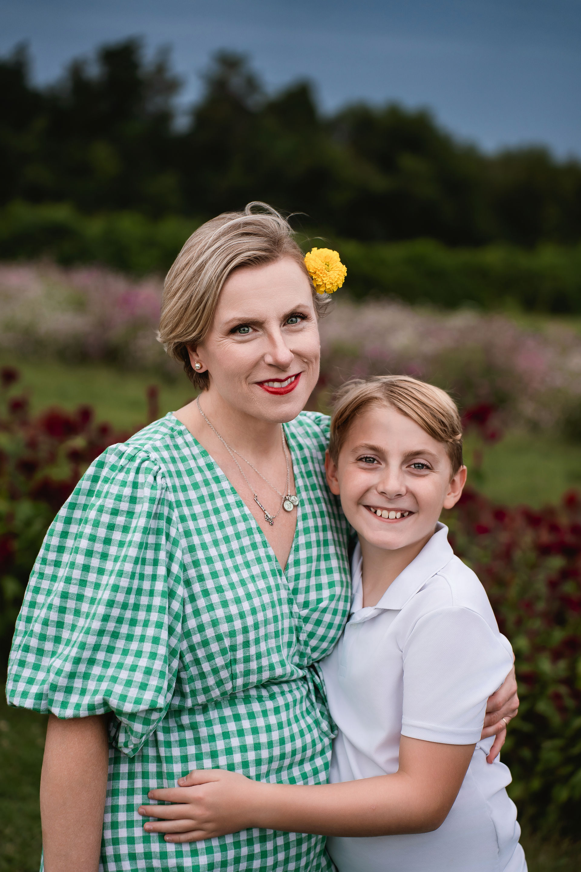 Des Moines and Norwalk, Iowa family photographer - mother and pre-teen sun embrace  and smile in a flower field.
