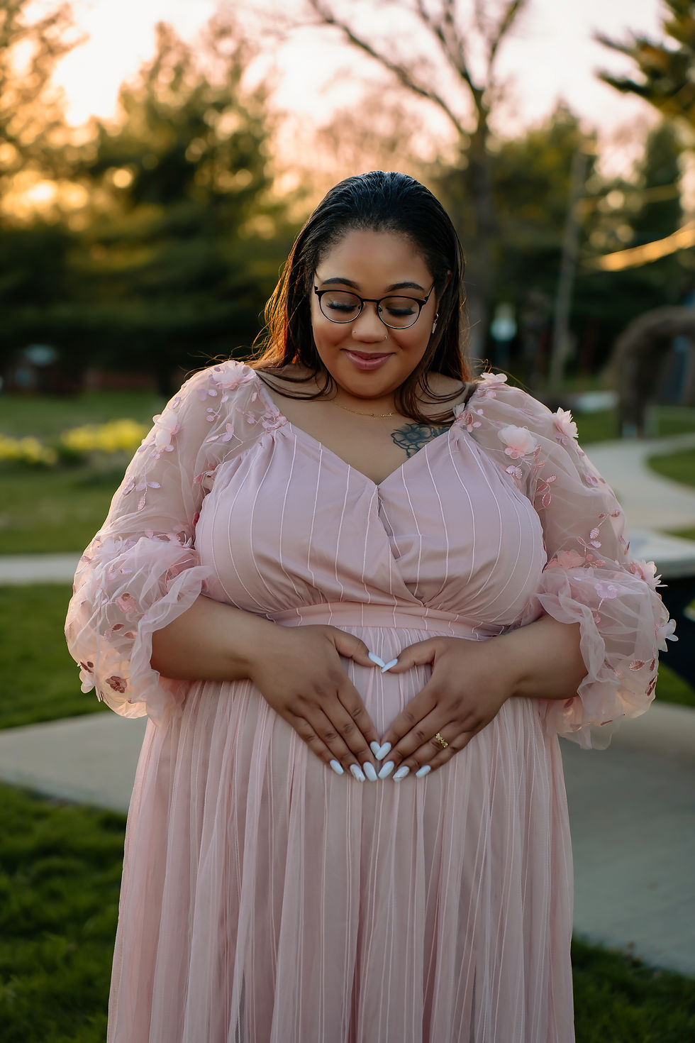 Des Moines, Iowa maternity photographer - pregnant black female makes a heart with her hands over her belly.
