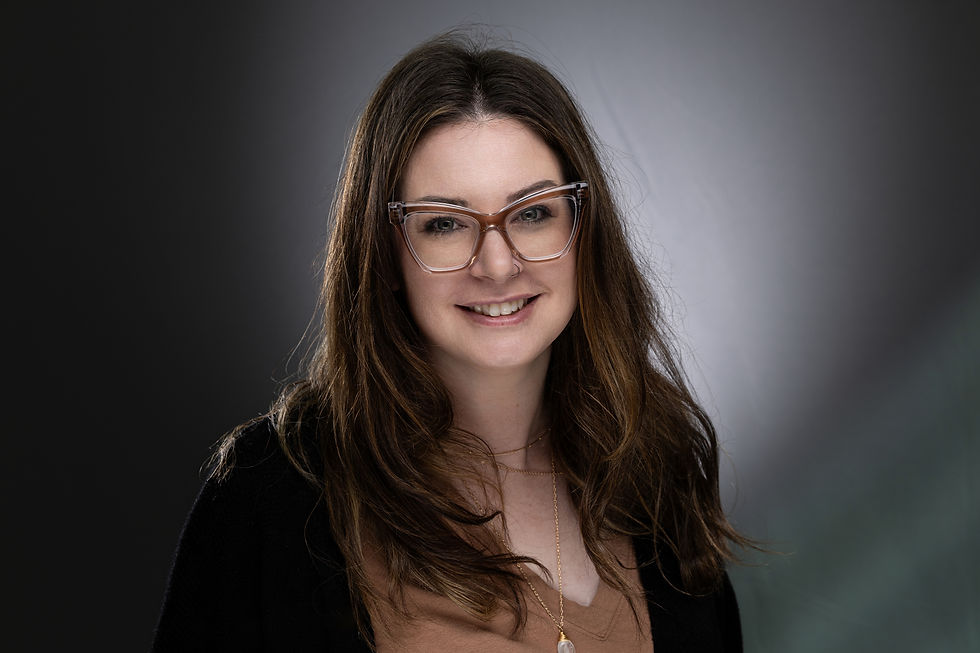 Des Moines, Iowa - headshot photographer - adult woman with brown hair and black sweater and brown shirt and brown vintage glasses is smiling for a business headshot.