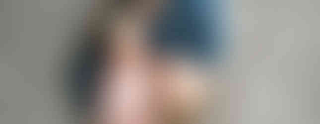 Des Moines and Norwalk, Iowa newborn photographer - a school-aged big brother poses on a gray rug with his newborn sister.