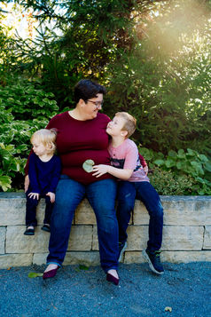 Des Moines, Iowa family photographer - mother of two snuggles her school-aged boy and toddler girl outdoors.