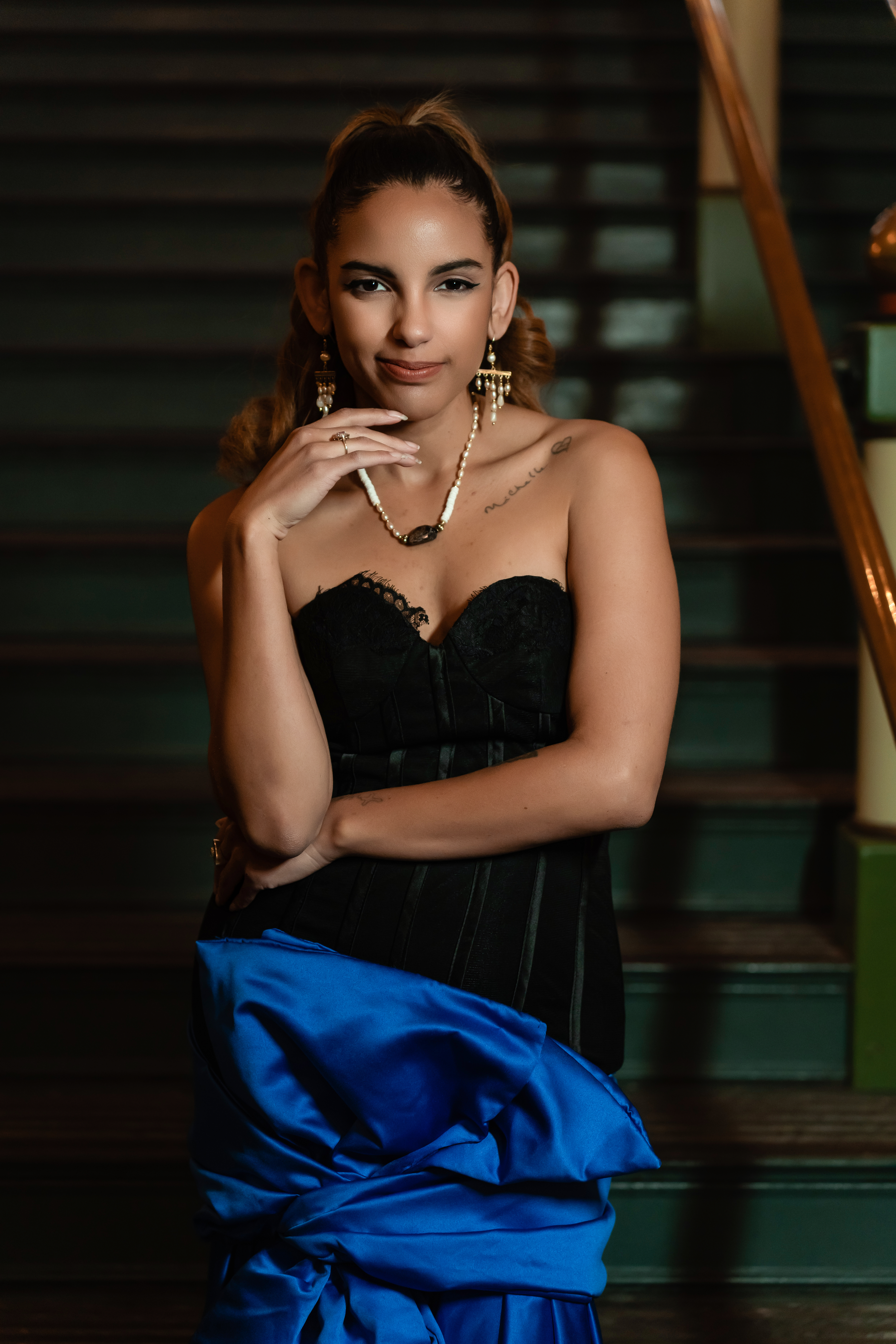 Des Moines, Iowa glamour and boudoir photographer - woman in a two-toned black and blue evening gown is photographed on a grand staircase.