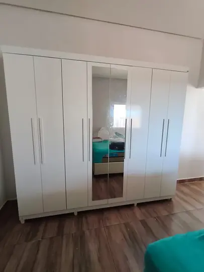 Montador de moveis instalando guarda roupa branco 8 portas com espelho