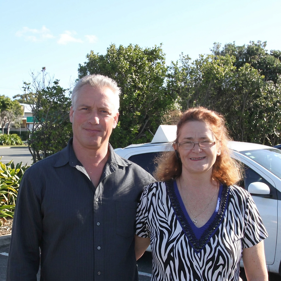 Man and woman standing next to a driving school car