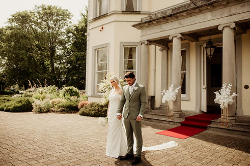 bride and groom with white pedestal arrangement at main entrance hazelwood floristry.JPG