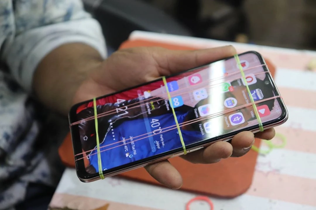 Person holding cracked phone screen needing repair