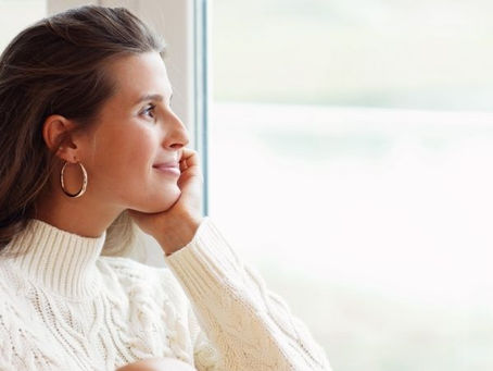Mujer junto a una ventana con luz cálida, reflexionando antes de volver a enamorarte